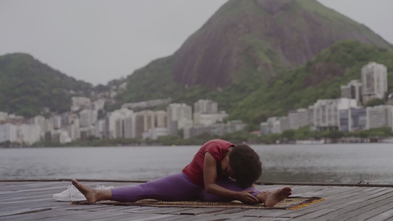 Mulher praticando ioga e alongamento ao ar livre em um cais.