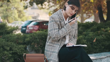 female entrepreneur writing in notepad while resting outdoor.