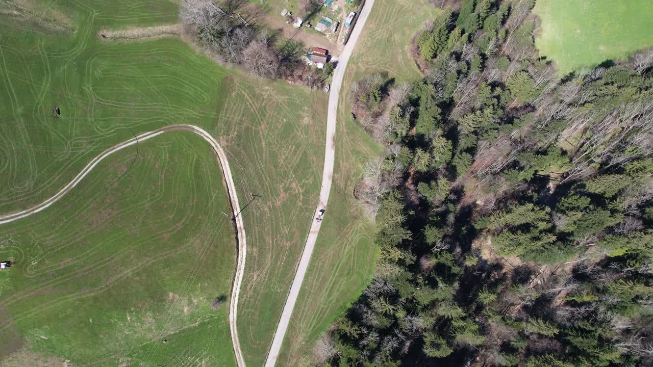 antena de arriba hacia abajo siguiendo la conducción de un tractor en una pequeña calle en los alpes suizos