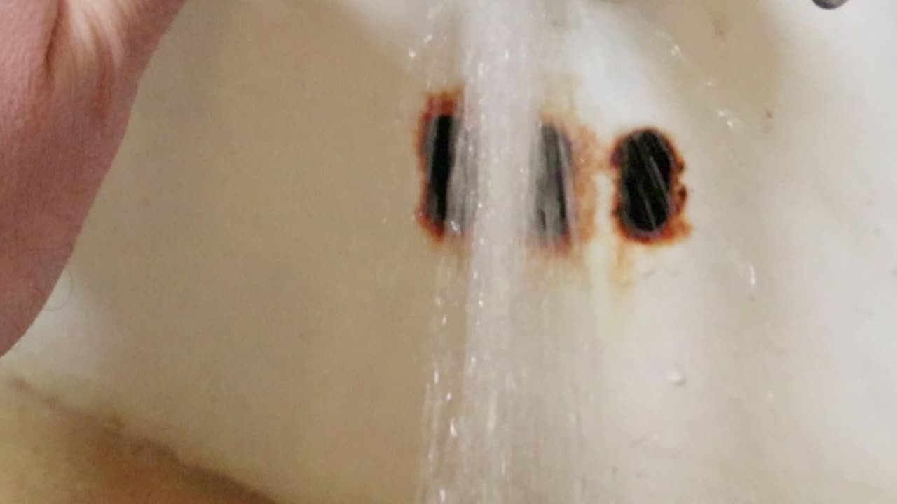 Turning on a rusty faucet with running water in slow motion.