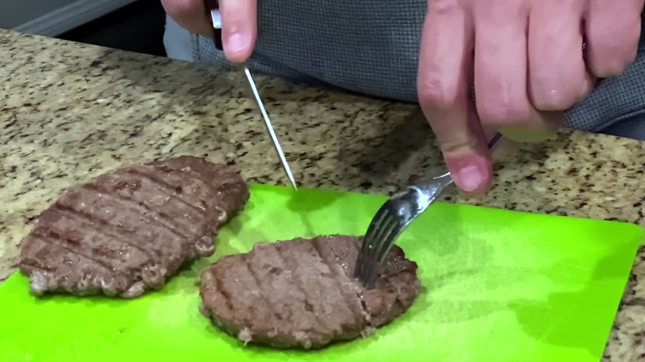 Slow motion, cutting pieces of cooked beef hamburger patties, meat grilled in house