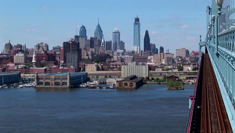 a rapid transit train drives across ben franklin bridge away from philadelphia pennsylvania