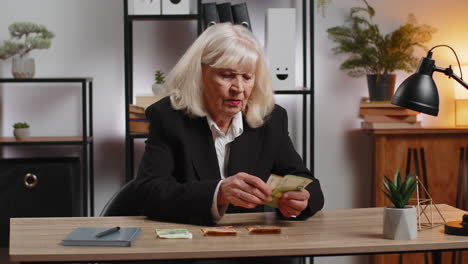 excited senior businesswoman counting cash money dollar checking salary enjoy richness at workplace