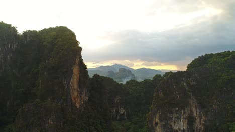 aerial. increíble video de estilo cinematográfico de enormes montañas y selva tropical en el sur de tailandia. vuelo de drones a través del pico. llamaradas solares detrás de las montañas. vuelo de dos pájaros cerca del cuadrocóptero.