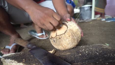 man breaking open coconut with machete