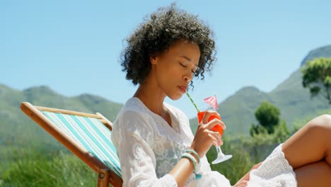 Side-view-of-young-mixed-frace-woman-relaxing-on-sun-lounger-in-the-backyard-of-home-4k