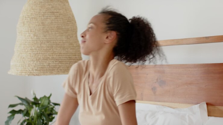 Donna che si rilassa a letto usando lo smartphone, godendosi il tempo libero, a casa