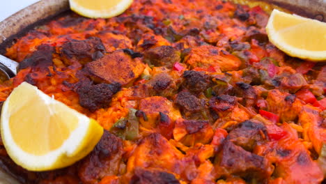 plato tradicional español de paella con pollo, verduras y rebanadas de limón en un restaurante, deliciosos mariscos en marbella españa, 4k tiro