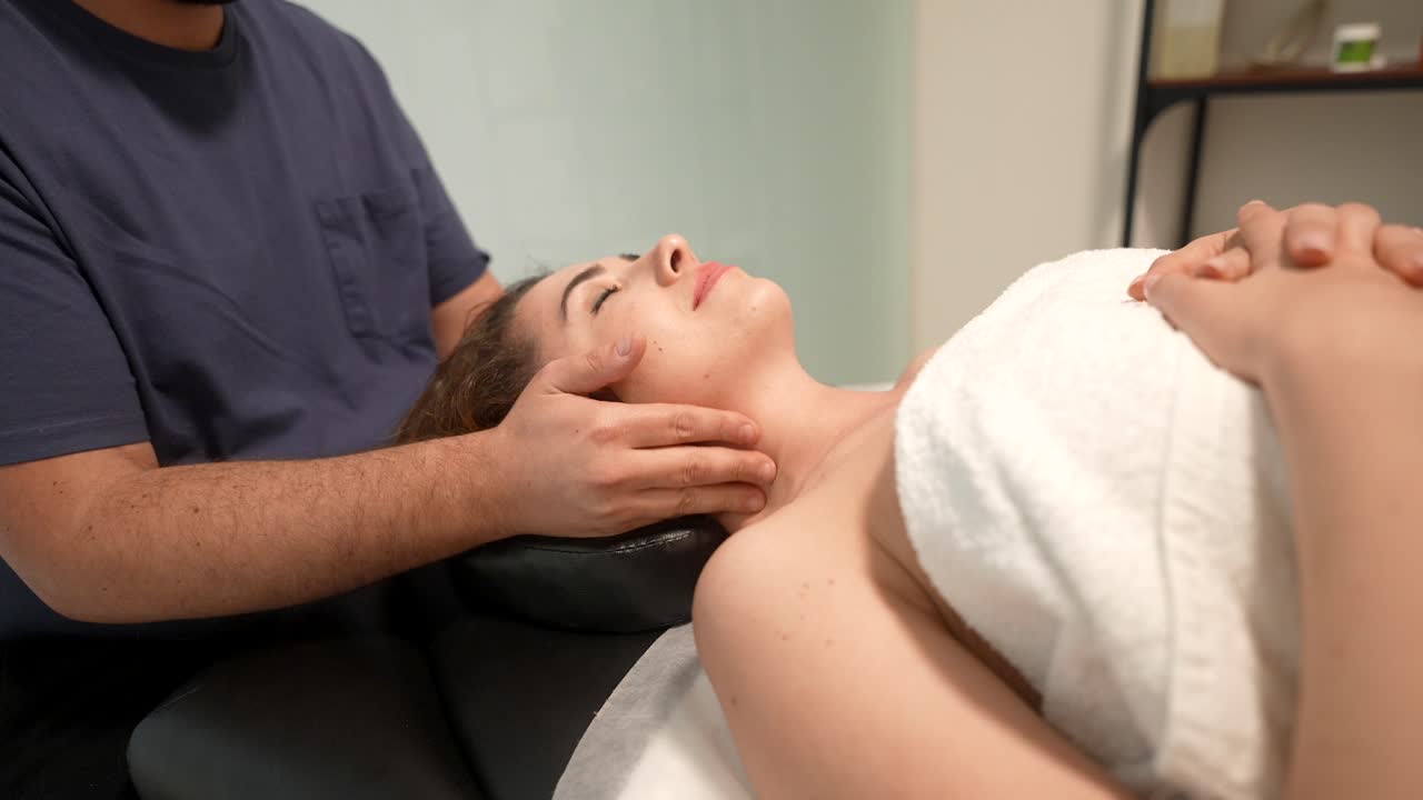 Therapeutin gibt einer Frau Nacken- und Gesichtsmassage