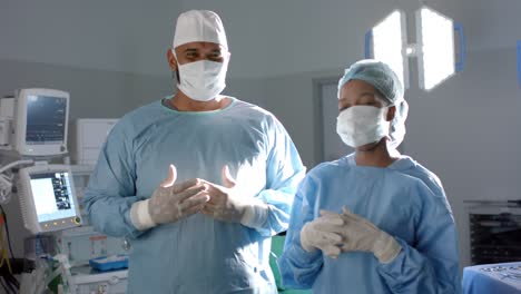 Portrait-of-diverse-surgeons-wearing-surgical-gowns-in-operating-theatre,-slow-motion