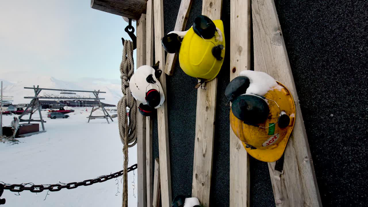 Hard hats and safety helmets hanging on the side of a wall in the mining town of Svalbard.