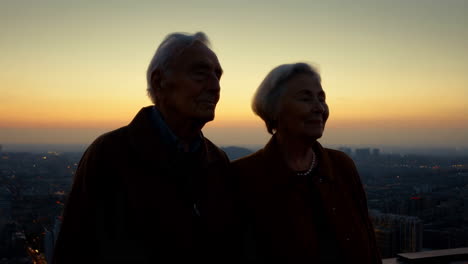 an elderly couple admiring the sunset city view
