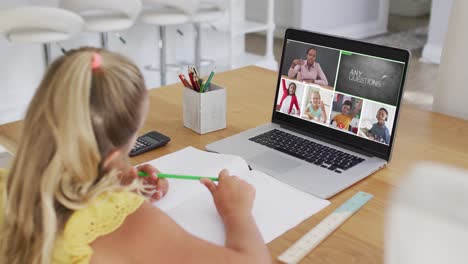 caucasian girl having a video conference with teacher and classmates on laptop at home