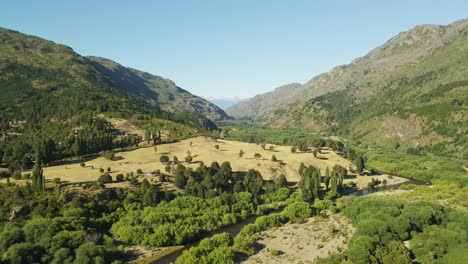 dolly out elevándose volando sobre el valle del hoyo rodeado por un bosque de pinos y montañas andinas, chubut, patagonia argentina