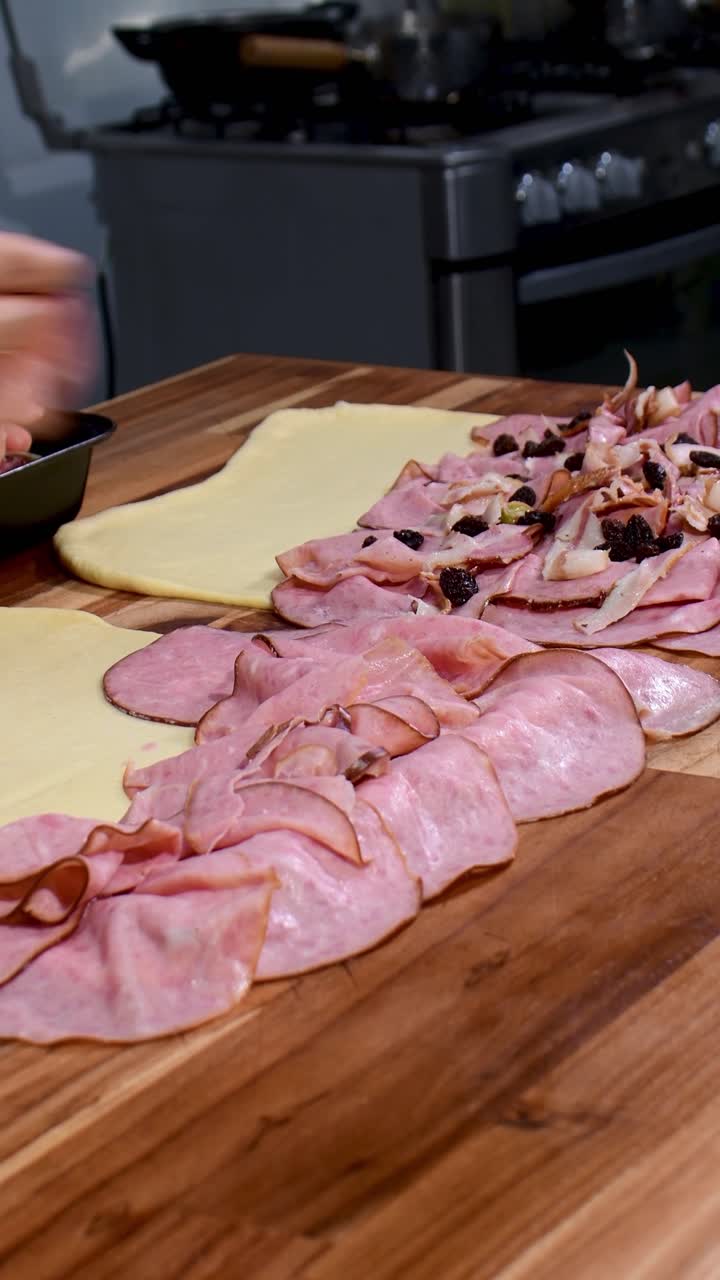 Mettere prosciutto cotto a fette rosa e uvetta sull'impasto per fare un pan de jamón.
