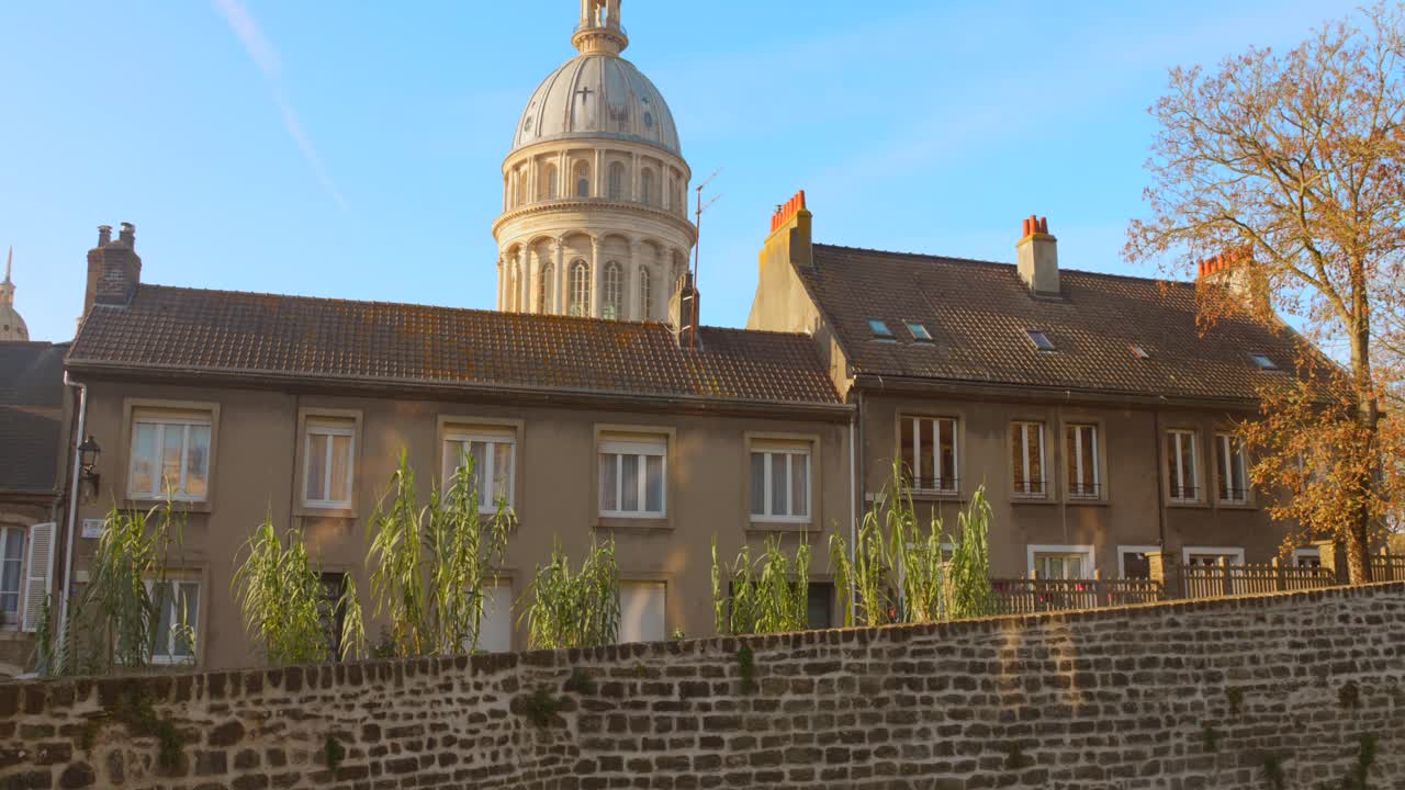 Shot of the Basilica of Notre-Dame dome rising above the rooftops of Boulogne-sur-Mer, France. The video captures the architectural contrast between the historic dome and the surrounding urban;