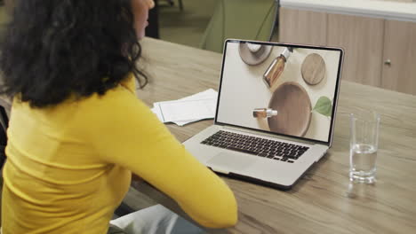 Biracial-woman-at-table-using-laptop,-online-shopping-for-aromatherapy-products,-slow-motion