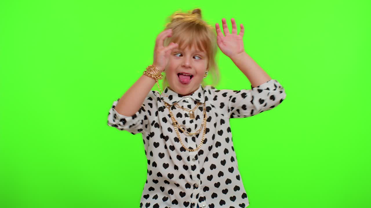 Funny child kid girl making playful silly facial expressions and grimacing, fooling, showing tongue