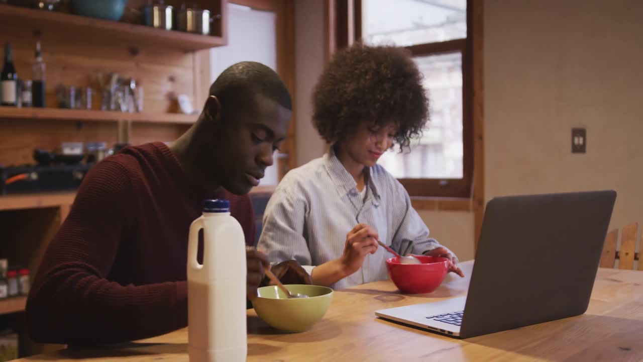 Couple watching computer while having breakfast