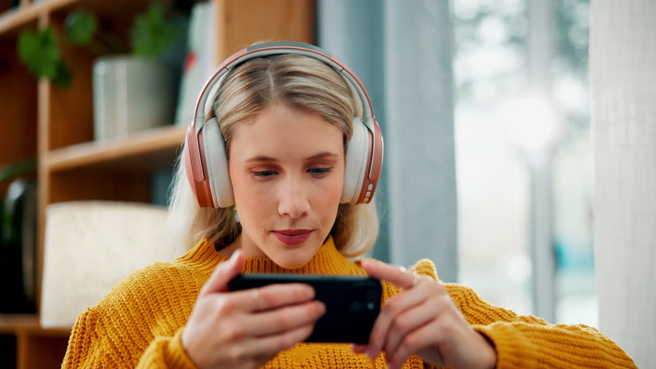 Woman playing game on mobile phone with headphones