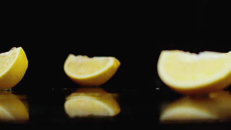 Un-Jugoso-Limón-Amarillo-En-Rodajas-Cayendo-Sobre-Un-Vaso-Con-Salpicaduras-De-Agua-En-Cámara-Lenta-Sobre-Un-Fondo-Oscuro