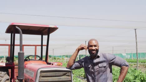 Video-of-happy-african-american-man-standing-in-front-of-tractor