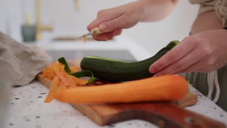 woman approaching kitchen sink to peel cucumber