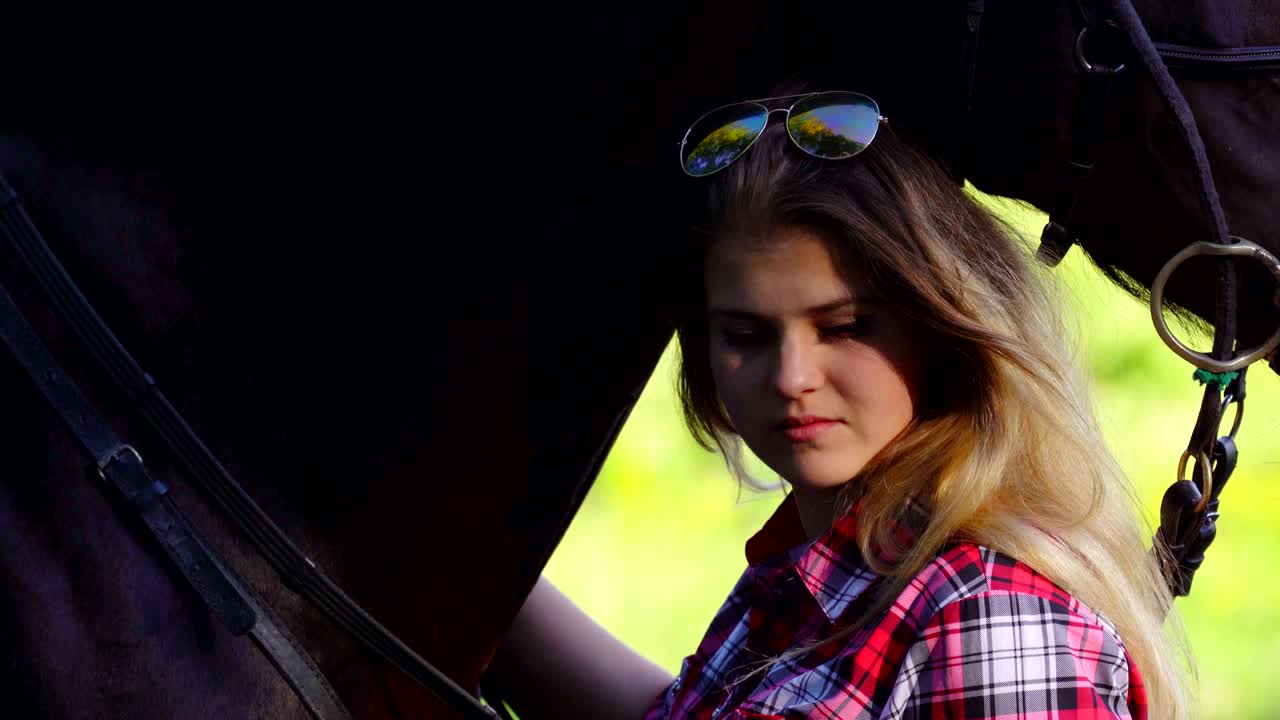 una joven rubia con una camisa a cuadros da un paseo con su caballo. una noche soleada de verano.