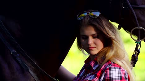 young blonde woman in a plaid shirt takes a walk with his horse. summer sunny evening.