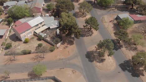 aerial follow shot of a car driving in a suburb crossing a small intersection