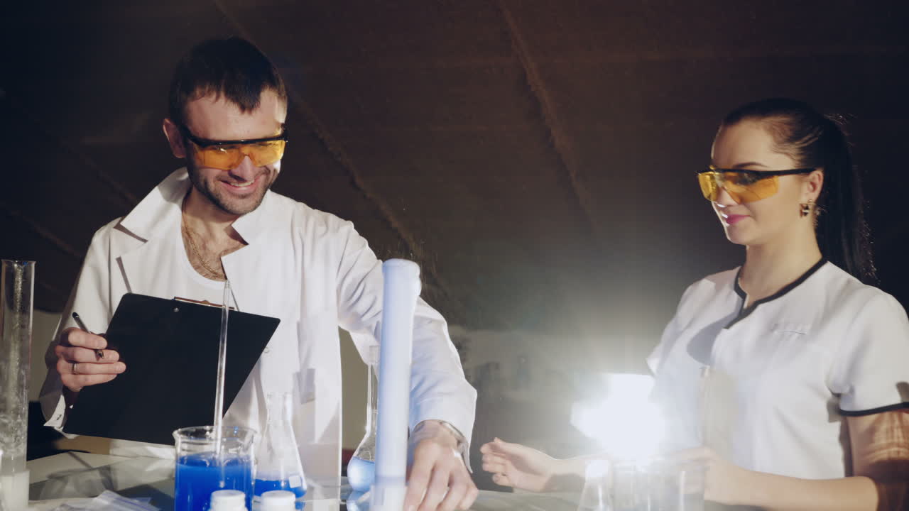 Two scientists are working in laboratory. Young female researcher and her senior supervisor are doing investigations with test tubes.