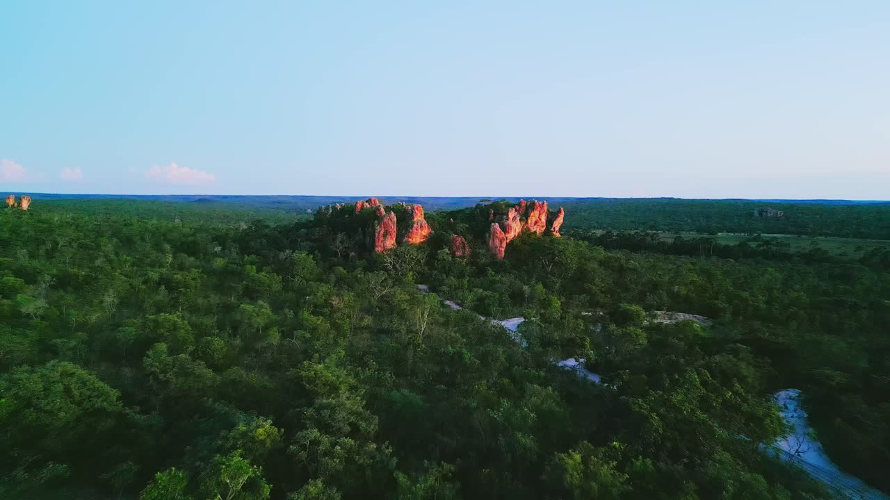 Warm sunlight illuminating Pedra do Gaviao, a striking rock formation in Brazil's lush Cerrado savannah, showcases the area's natural beauty and tranquility at sunset