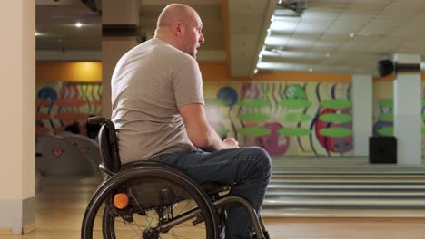 two young disabled men in wheelchairs playing bowling in the club