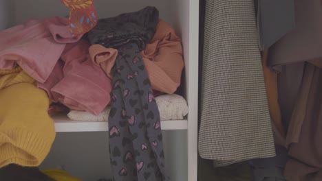 a cluttered and messy closet shelf filled with a disorganized pile of various clothes