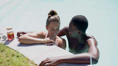 smiling diverse couple relaxing in swimming pool, enjoying summer day together