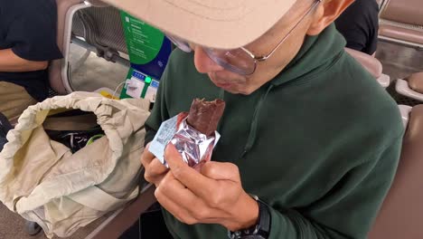 person unwraps and enjoys chocolate during commute