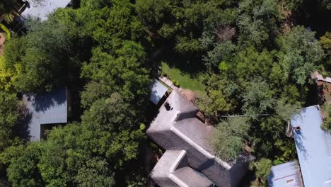 Aerial-top-spinning-Shot-over-accommodation-surrounded-by-lush-green-vegetation-outside-Kruger-National-Park,-South-Africa-at-daytime