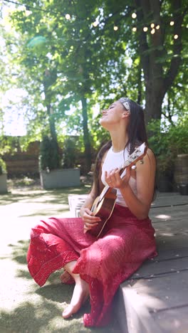 young woman playing ukulele in a garden