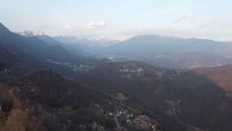 Roads-and-towns-in-majestic-mountain-landscape-with-forest-and-snowy-peaks,-aerial-view