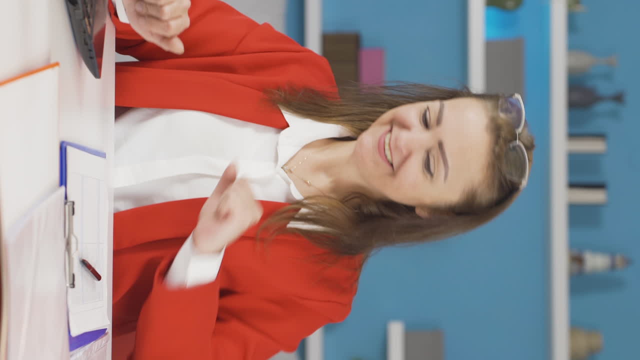 video vertical de una mujer que trabaja en una oficina en casa leyendo buenas noticias y sintiéndose feliz.