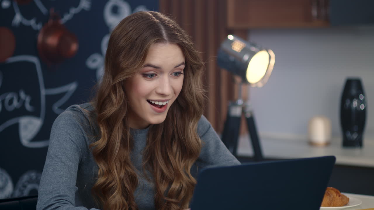 mujer de negocios recibiendo buenas noticias en la computadora en casa. chica feliz trabajando en casa