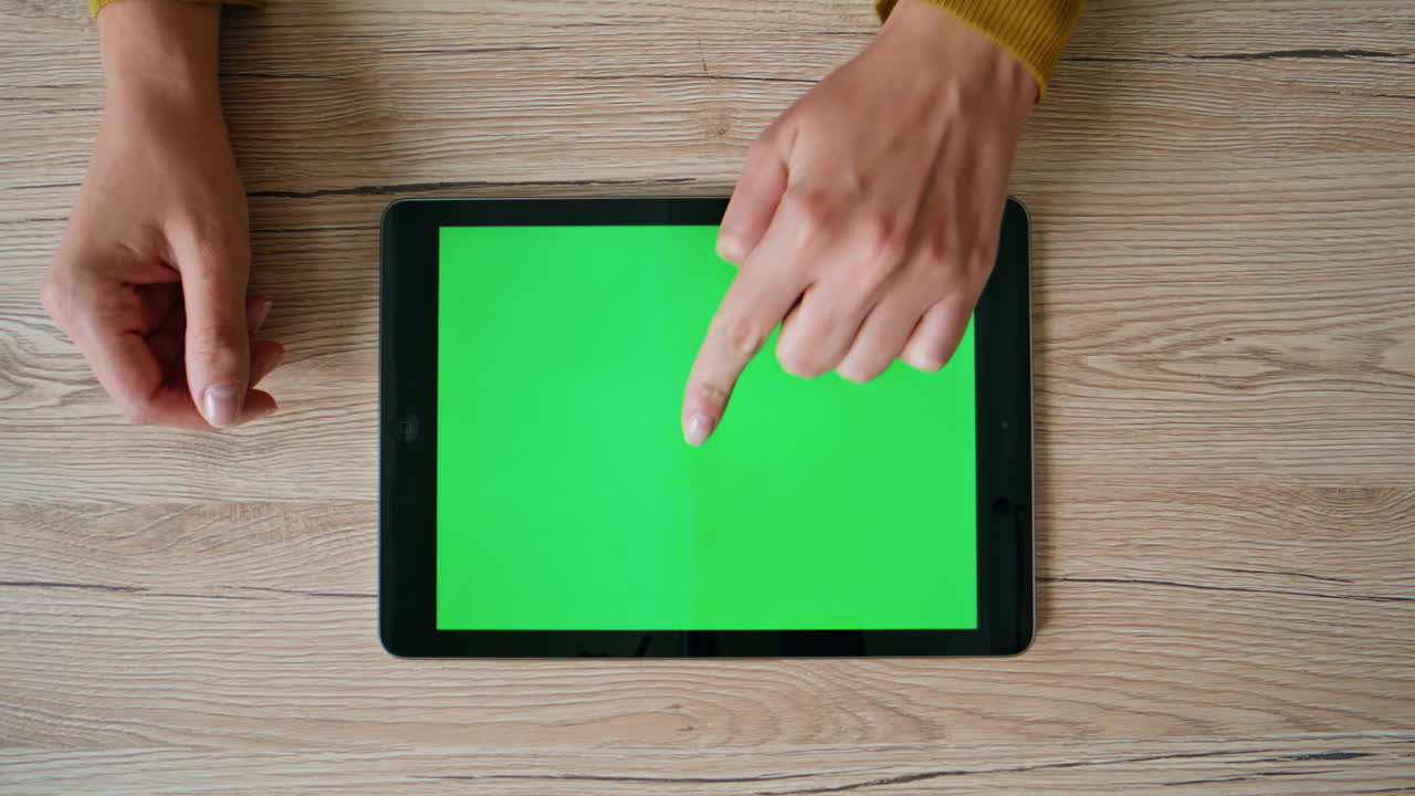 Hands choosing purchases chroma key tablet in home table closeup. Unknown woman