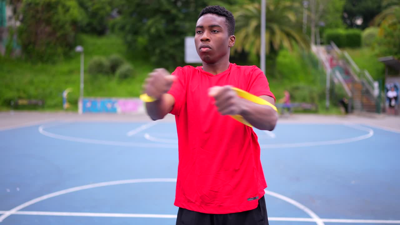 Man exercising with resistance band on basketball court