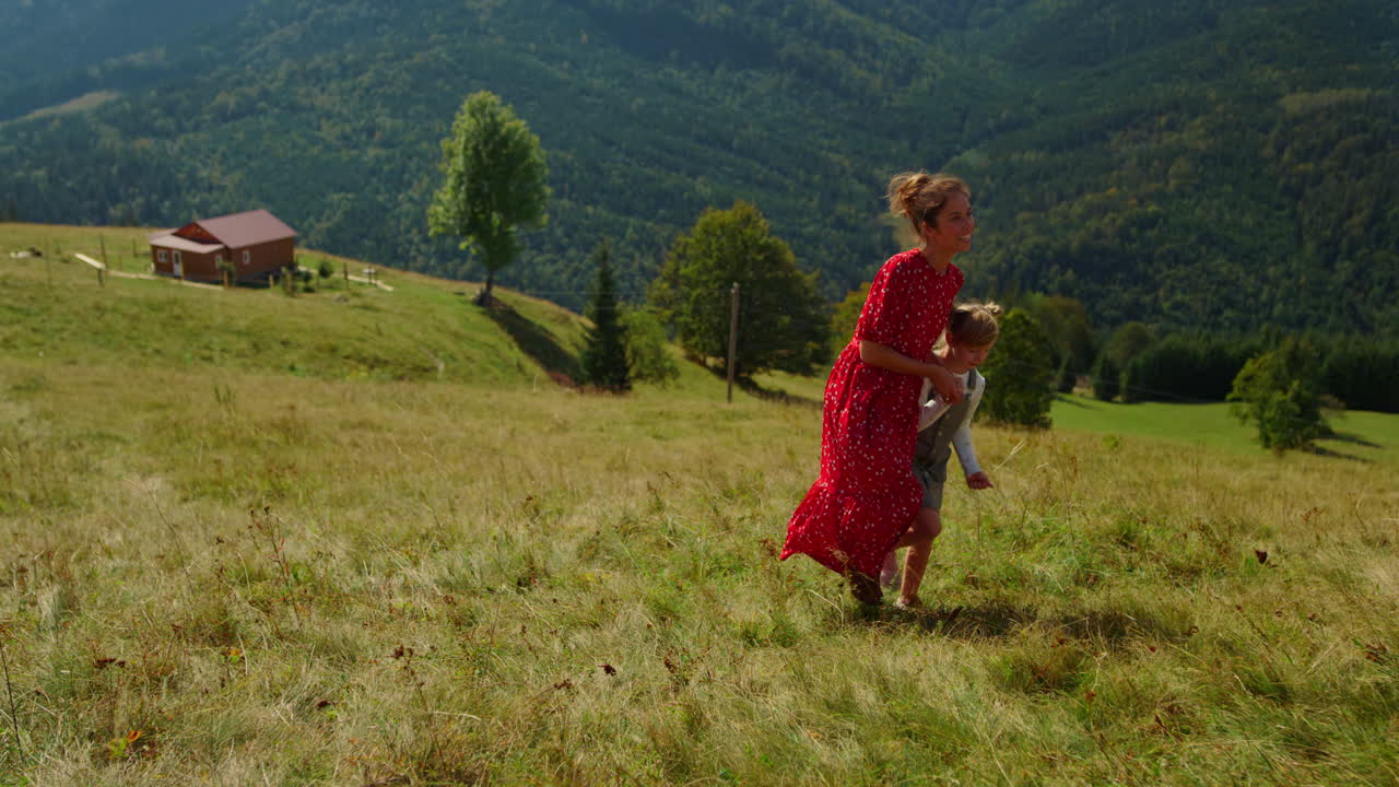 madre feliz caminando hija en la colina de la montaña. mujer señalando con el dedo a las vistas.