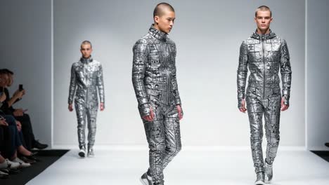 futuristic fashion showcase: models strut in innovative metallic outfits with distinct geometric patterns on the runway, captivating audiences with style and edge