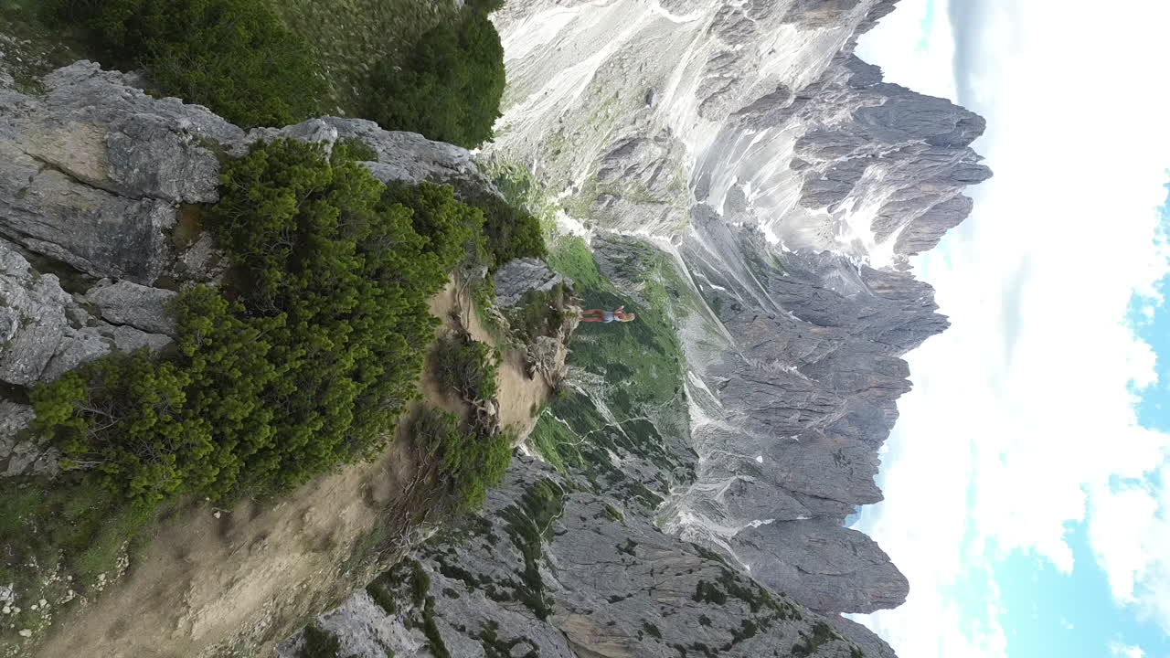 Hermosa chica rubia de pie en la cima del Mirador Cadini di Misurina, Dolomitas, Italia, Europa, vista de dron en retroceso