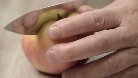 slicing a juicy red and yellow apple in half with a sharp knife