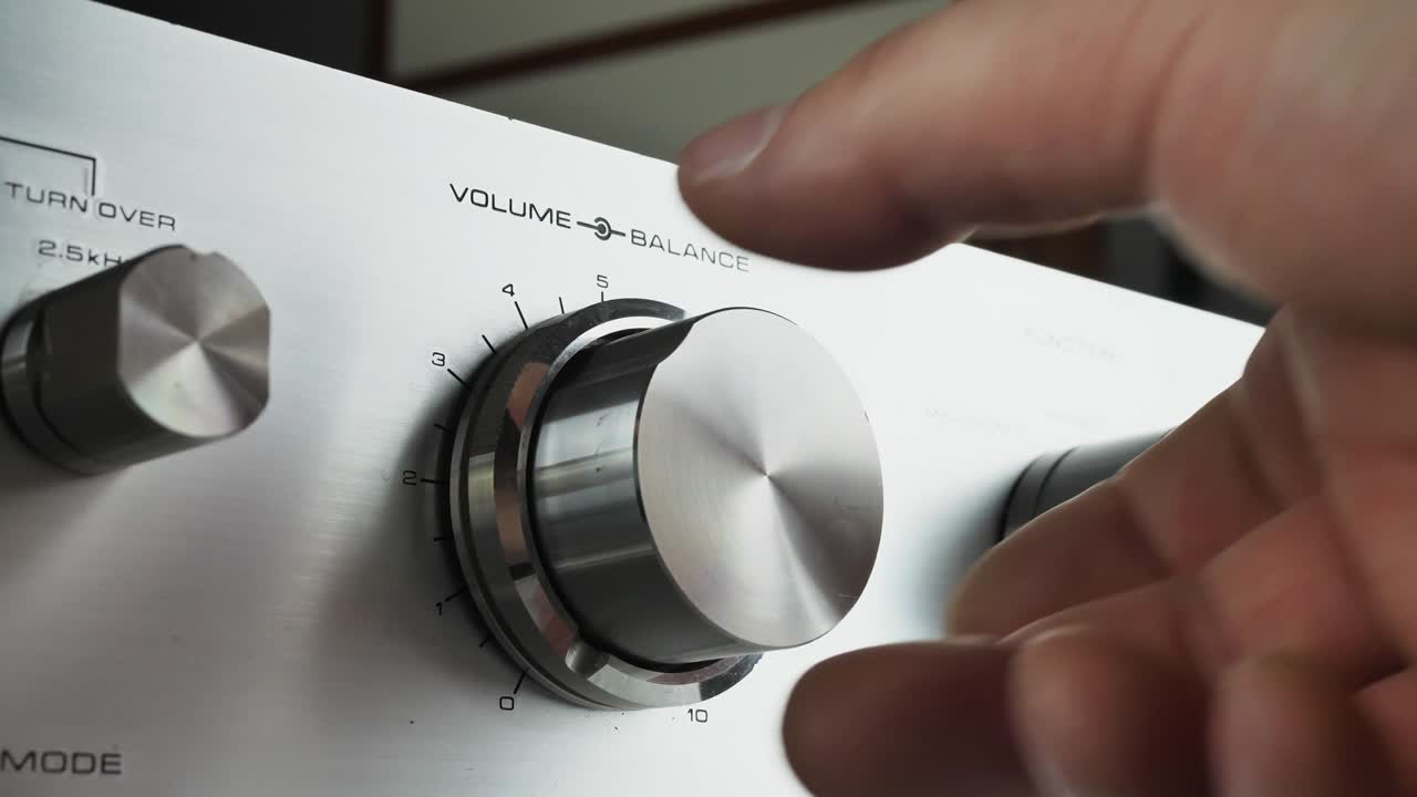 손은 라디오의 볼을 조절하고 반이는 회색 패널에서 다양한 fm 방송국을 전환합니다.