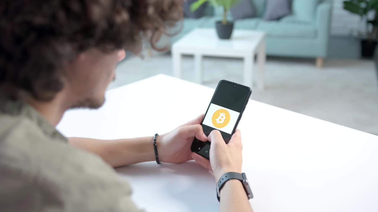 joven mirando concentrado en el teléfono en sus manos, pensando en cripto, bitcoin