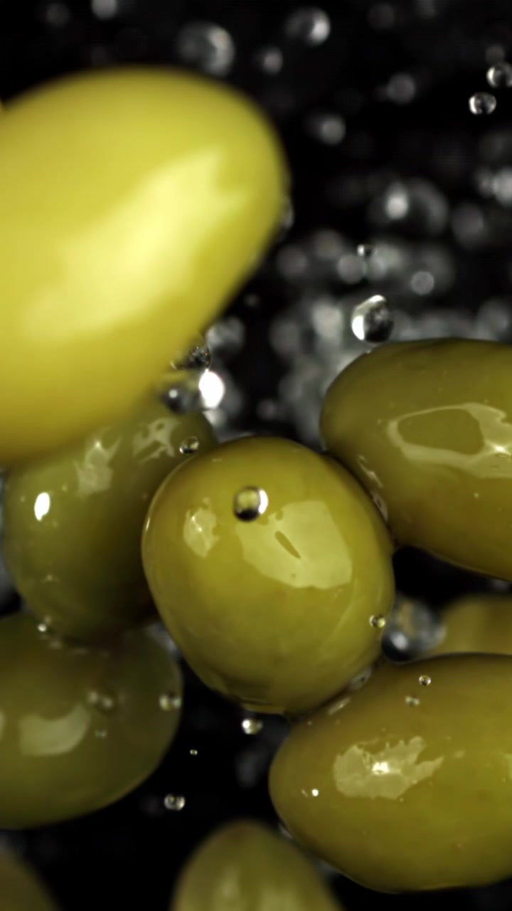 Olive verdi fresche con goccioline d'acqua che cadono al rallentatore.